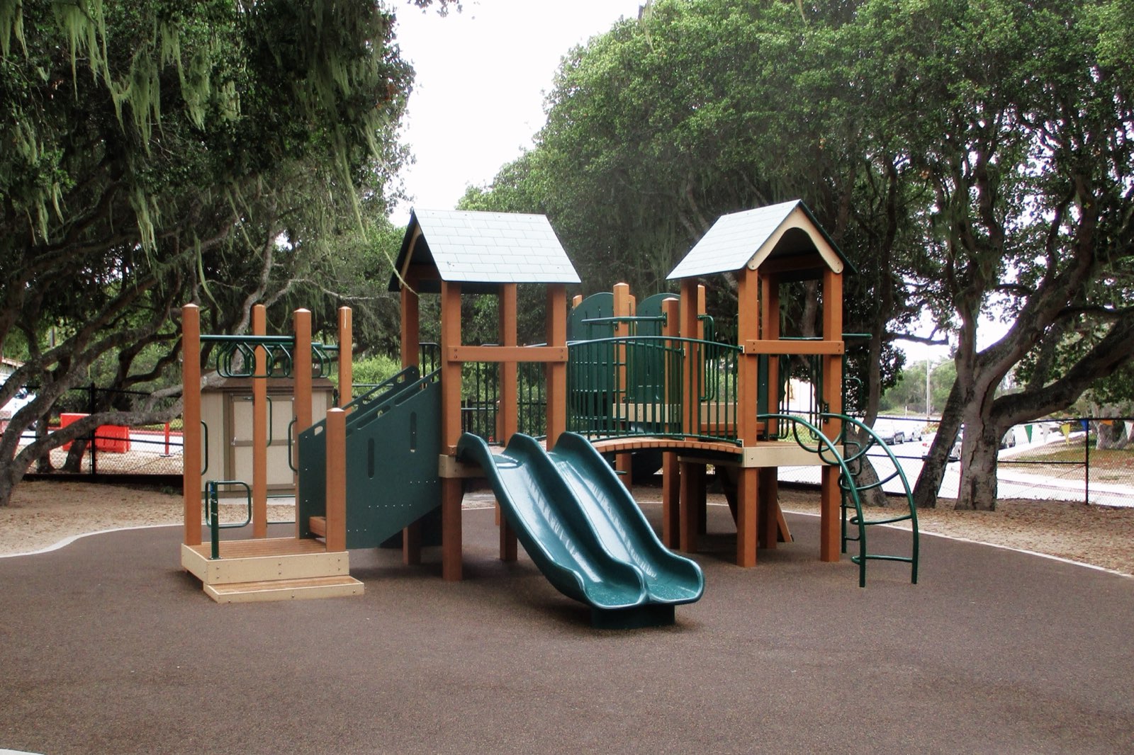 Recycled plastic lumber play structure with twin slides under mature oaks